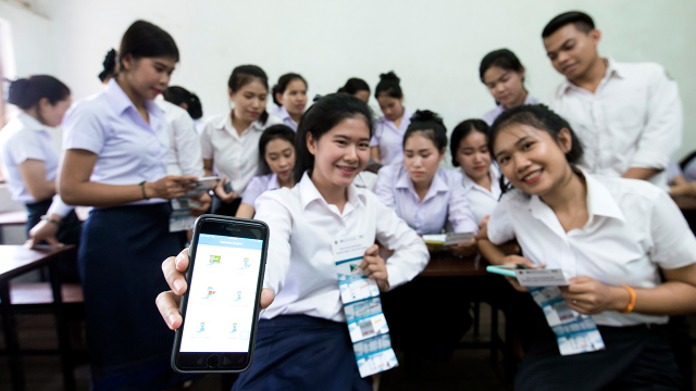groupe d'étudiants dont une jeune fille montrant l'interface de son téléphone portable