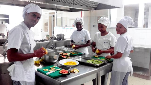 Four smiling Cape Verdean student chefs peel fruits
