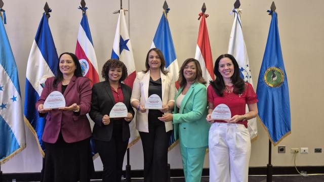 Five women from Latin America standing with the flags of the Latin America and Caribbean zone in their hands, holding their prize.