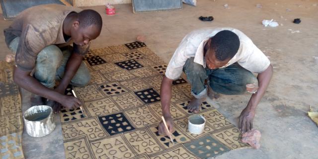 Jeunes hommes peignant une toile au sol