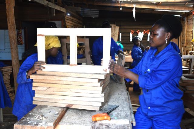 Two African women survivors of gender-based violence making wooden windows