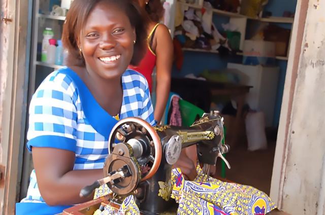Jeune femme africaine souriante faisant de la couture