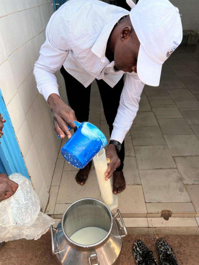 Un homme transvasant du lait dans une verre mesureur afin de contrôler la qualité du lait