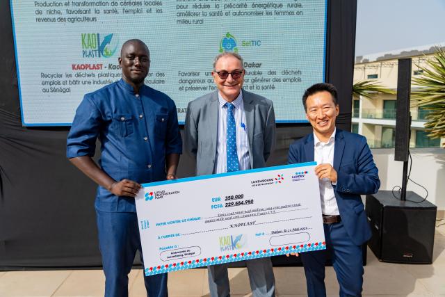 Remise d'un chèque symbolique entre trois hommes