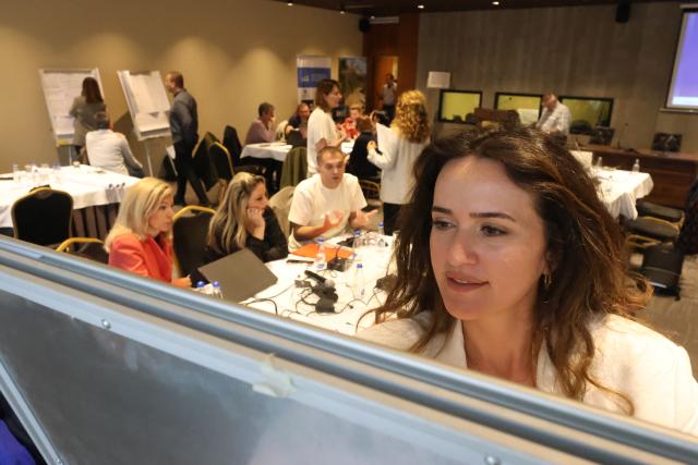 Workshop participant at white board with people co-working in the backround