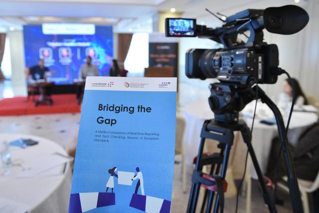 Front page of publication and TV camera filming a panel discussion at a conference